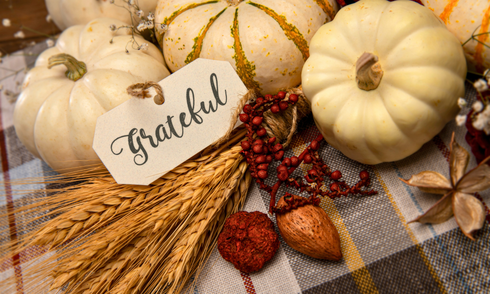 White pumpkins on plaid table with a tag saying grateful in calligraphy